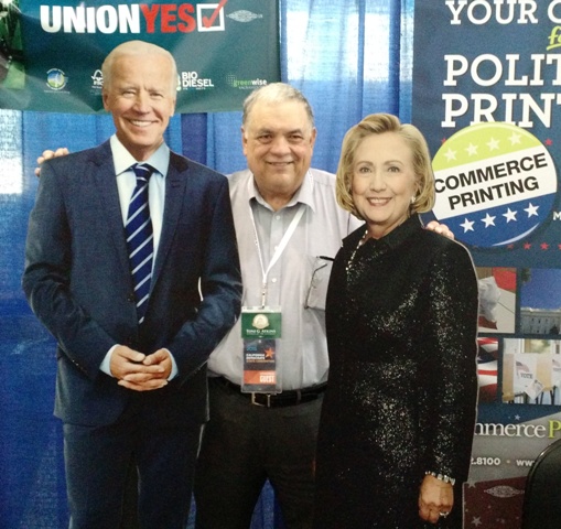 A campaign worker with cutouts of Biden and Clinton. Sanders is out of view on the left. 